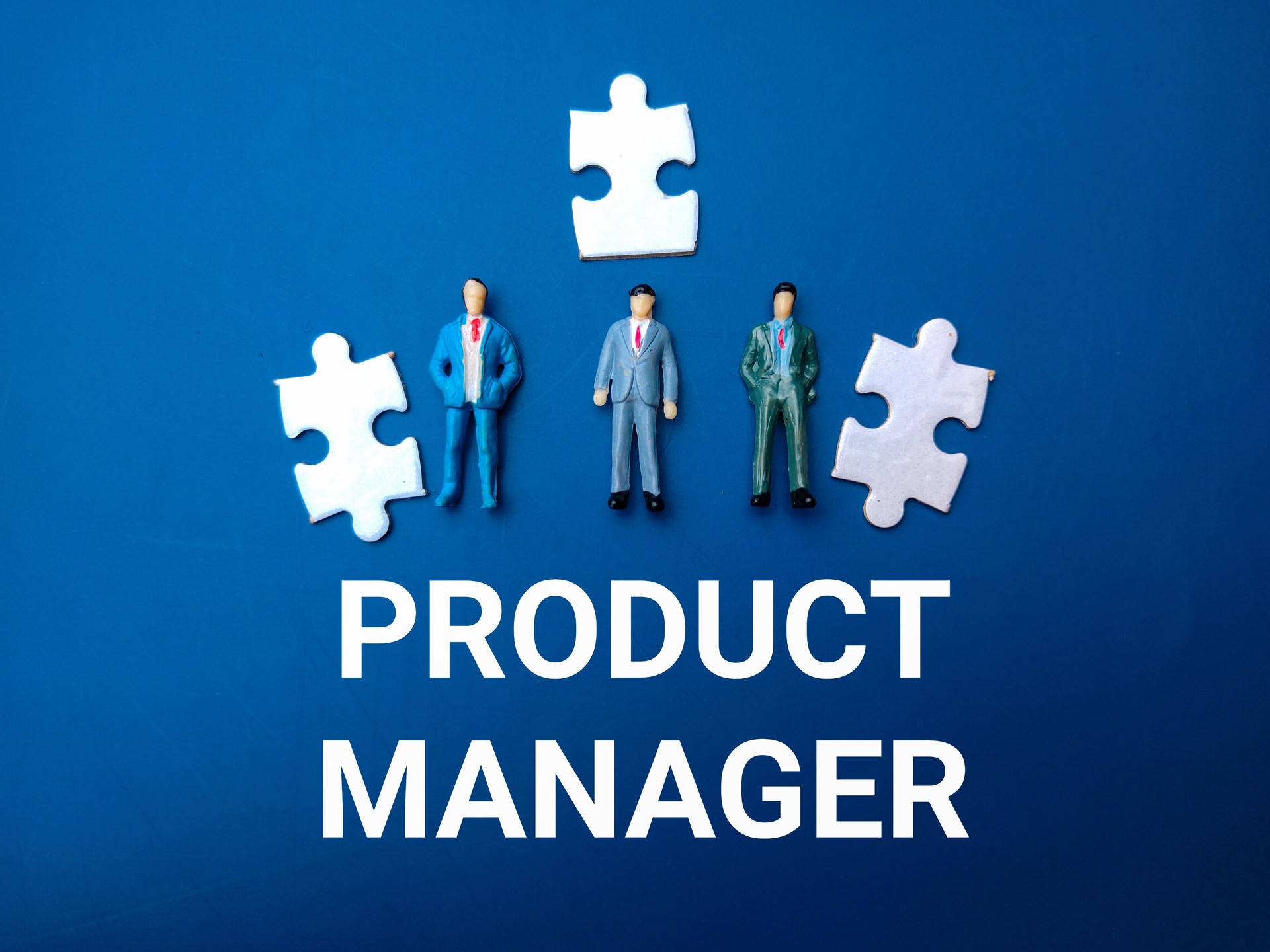 Miniature people and white puzzle with the word PRODUCT MANAGER